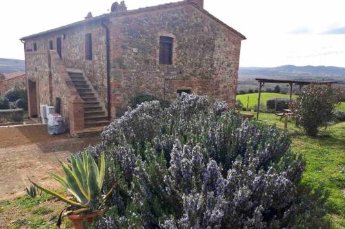 an old stone building with purple flowers in front of it at Casetta Tre Poderi appartamento Papaveri in Monte Cucco