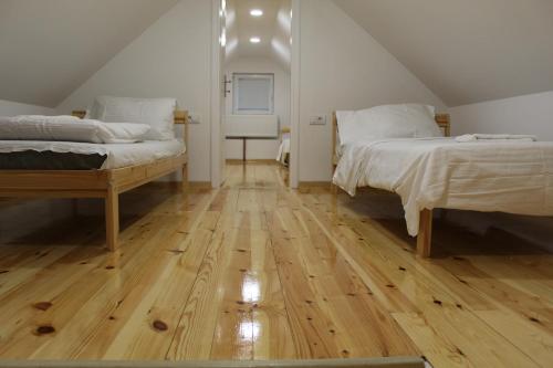 a bedroom with two beds and a wooden floor at Kucica u Šumi in Užice