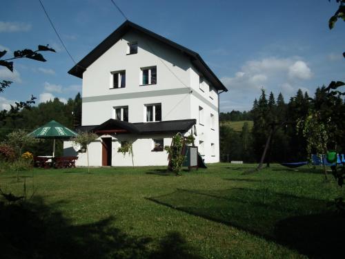 duży biały dom z czarnym dachem w obiekcie Apartamenty Za Świerkami w mieście Tylicz