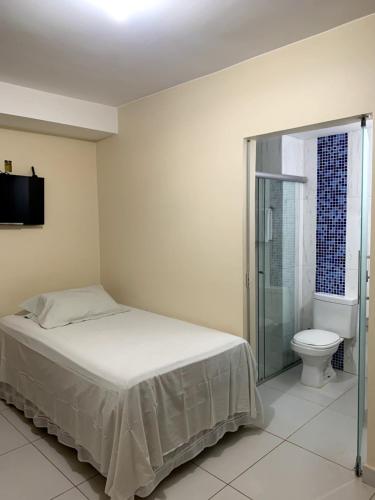 a bedroom with a bed and a bathroom with a toilet at Pousada Jardim Brasília in Brasilia