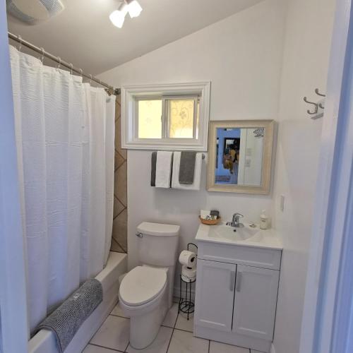 a white bathroom with a toilet and a sink at Knotty Pine Ocean Front Suite - Adults Only in Ingonish Beach