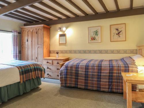 a bedroom with two beds and a wooden ceiling at Milkwood Cottage in Fishguard