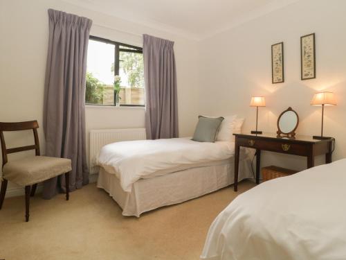 a bedroom with two beds and a desk and a window at 1A Erneston Crescent in Corsham