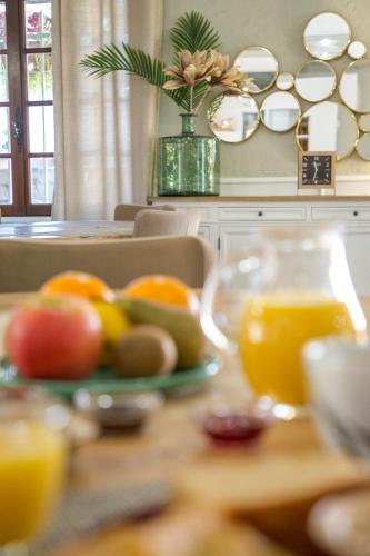 a table with a plate of fruit and orange juice at Les Pins Blancs en Provence in Le Muy