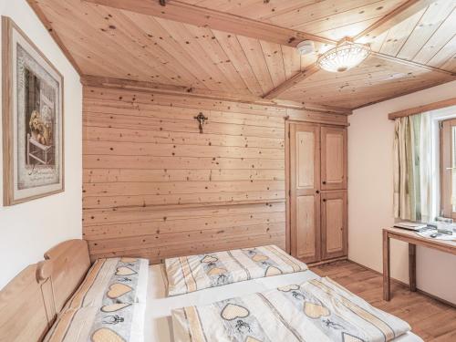 two beds in a room with a wooden wall at Urlaub am Bauernhof Feldbauer in Landl