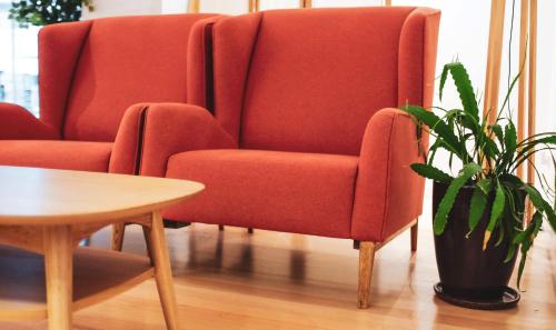 a red chair and a table and a potted plant at Trinity Hotel in Wellington