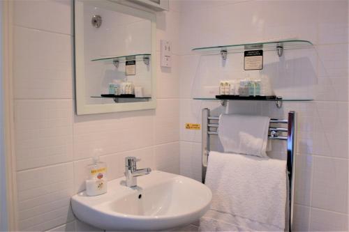 a white bathroom with a sink and towels at The P&M Paignton RESIDENCE in Paignton