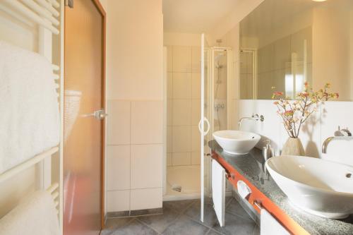 un bagno con due lavandini e una doccia di Waldhotel Felsentor a Hauenstein