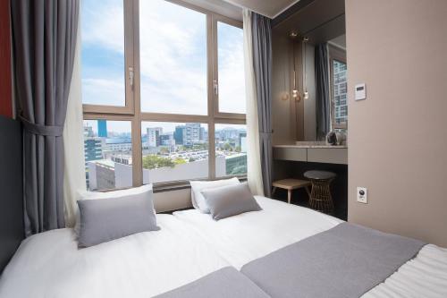 a hotel room with a bed and a large window at Utop Boutique Hotel&Residence in Gwangju