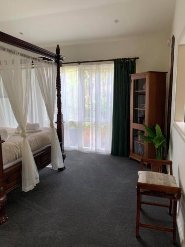 a bedroom with a canopy bed and large windows at Weeroona Bed And Breakfast in Rye