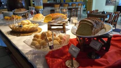 ein Tisch mit verschiedenen Brot- und Gebäcksorten in der Unterkunft Ilha flat Hotel Suíte Swaenen II in Ilhabela