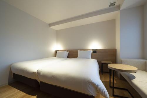 a bedroom with a large white bed and a table at Umekoji Potel KYOTO in Kyoto