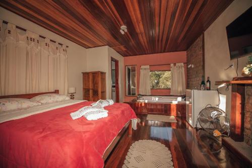 um quarto com uma cama vermelha e um lavatório em Sítio Recanto do Araçá em Visconde de Mauá