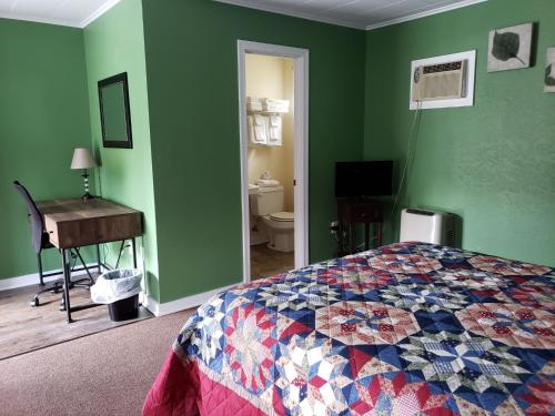 a bedroom with green walls and a bed and a piano at Blue Ridge Motel in Schroon Lake