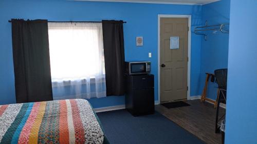 a room with a bed and a television and a door at Blue Ridge Motel in Schroon Lake