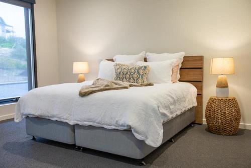 a bedroom with a bed with two lamps and a window at Johnnies in Robe