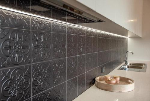 a kitchen with a black tile wall with a sink at Johnnies in Robe