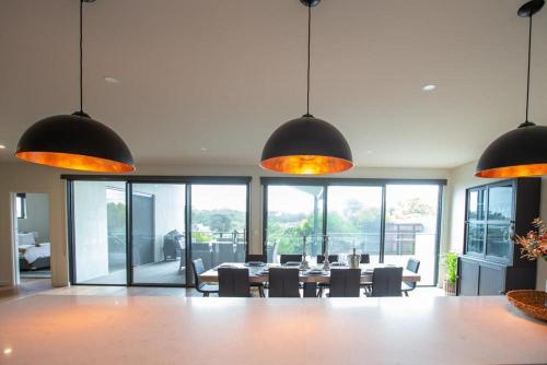 a dining room with a table and chairs and pendant lights at Johnnies in Robe