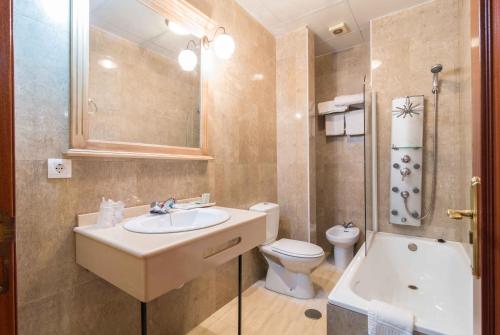 a bathroom with a sink and a toilet and a tub at Hotel Esmeralda in Osuna