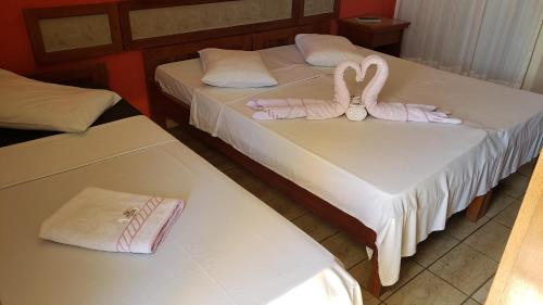 two beds with pink towels and two swans on them at Pousada Enseada do Corsário in Guarapari