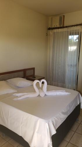 two swans shaped like hearts are on a bed at Pousada Enseada do Corsário in Guarapari
