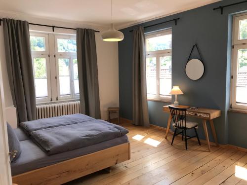 a bedroom with a bed and a desk and windows at Stilvolle Ferienwohnung im Herzen von Triberg in Triberg