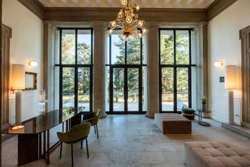 a large dining room with a chandelier and large windows at Hotel Villa Soligo - Small Luxury Hotels of the World in Farra di Soligo