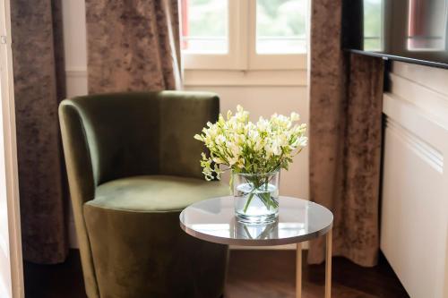 a green chair with a vase of flowers on a table at Hotel Villa Soligo - Small Luxury Hotels of the World in Farra di Soligo
