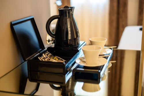 a black coffee pot sitting on a glass table with cups at Hotel Villa Soligo - Small Luxury Hotels of the World in Farra di Soligo
