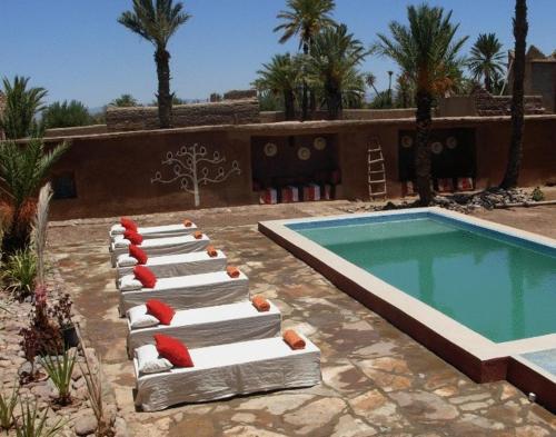 a row of lounge chairs next to a swimming pool at Dar Es Salam in Skoura