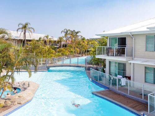 a pool at a resort with people swimming in it at Pacific Blue 245-265 Sandy Point Rd - Dual Key Access, air conditioned unit with resort facilities and linen supplied in Salamander Bay