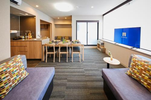 a room with a table and chairs and a kitchen at MONday Apart Premium HAMAMATSUCHO in Tokyo