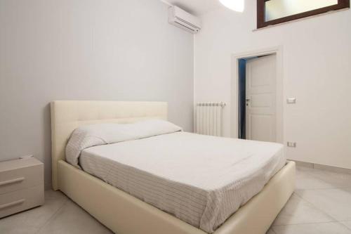 a white bedroom with a bed and a mirror at Baia degli Emiri in Lascari