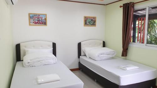 two twin beds in a room with a window at โรงแรม​ เดอะวิน​ รีสอร์ท in Thung Song
