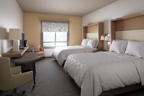 a hotel room with two beds and a desk and a window at Holiday Inn Richland on the River by IHG in Richland