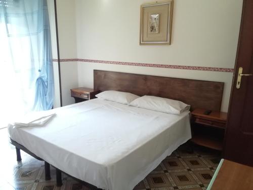 una camera con letto bianco e testiera in legno di Hotel La Carina a Grottaminarda