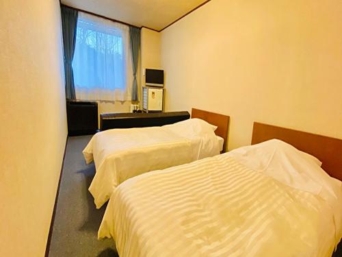 a hotel room with two beds and a window at Nangoku Hotel in Minamiboso