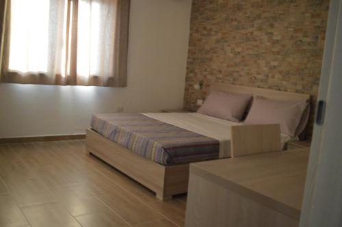 a bedroom with a bed and a brick wall at Affittacamere Sos Ninnitteddos in Torpè