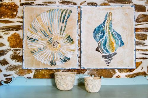 two pieces of art on a wall with two vases at Traditional Apartments Elafos in Elafonisi
