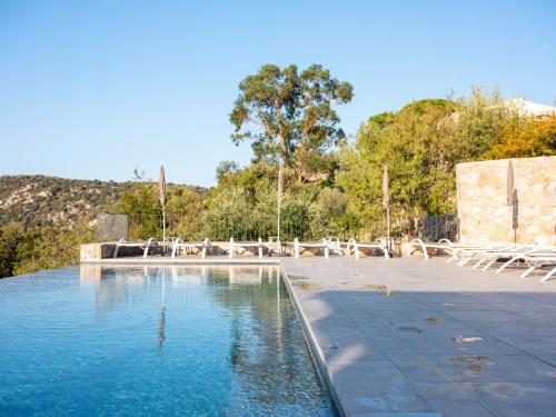 une piscine d'eau bordée de chaises et d'arbres dans l'établissement Hotel La Santa, à Santa-Reparata-di-Balagna