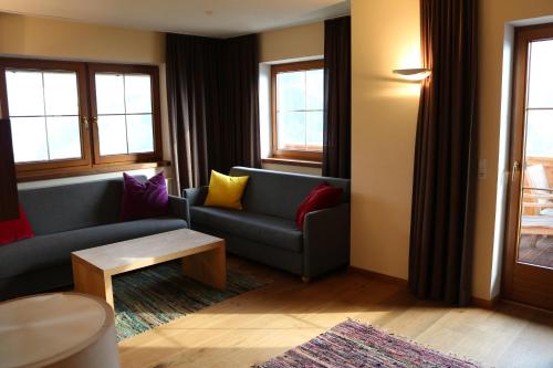 a living room with a blue couch and colorful pillows at DieAussicht - Refugium am Berg in Hippach