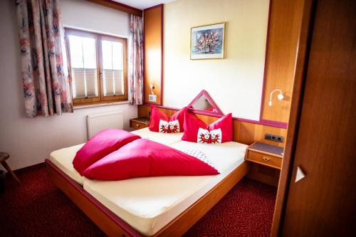 a hotel room with two beds with red pillows at Ferienhotel Angerhof in Fiss