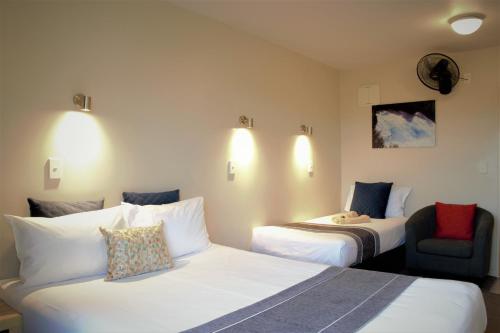 una habitación de hotel con 2 camas y una silla en Bella Vista Motel Taupo en Taupo