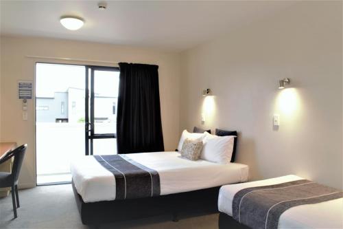 a hotel room with two beds and a sliding glass door at Bella Vista Taupo in Taupo
