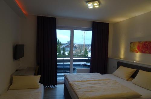 a bedroom with two beds and a large window at Aktiv Hotel Winterberg in Winterberg