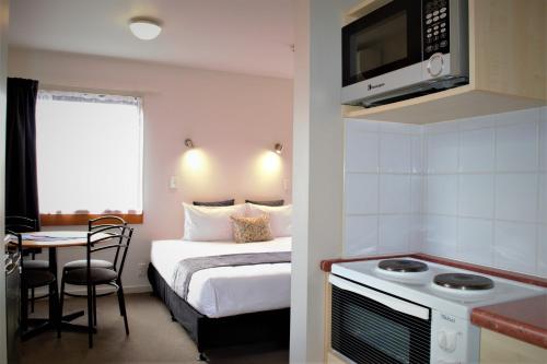 a small hotel room with a bed and a kitchen at Bella Vista Taupo in Taupo