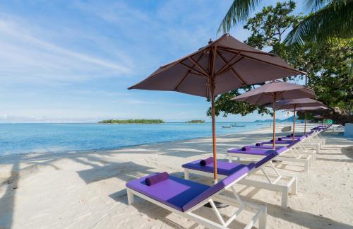 a row of lounge chairs and umbrellas on a beach at La Vida Samui in Chaweng