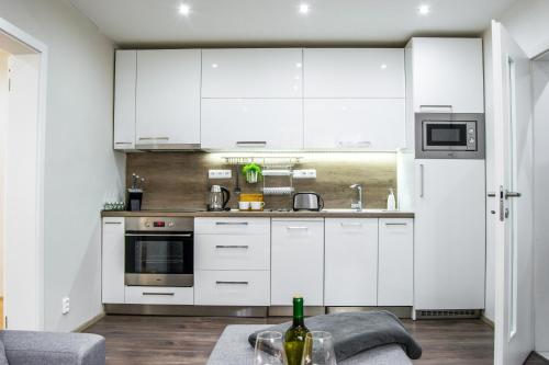 a white kitchen with white cabinets and a table at Apartment in downtown in Olomouc