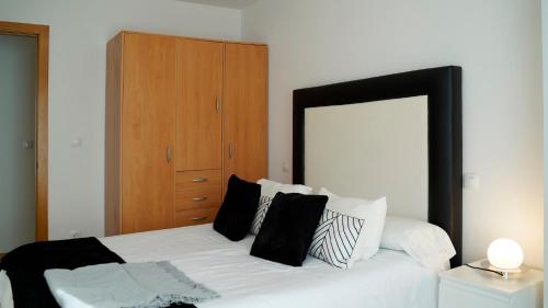 1 dormitorio con cama blanca y almohadas blancas y negras en Solares Style vistas al rio MIERA en Solares