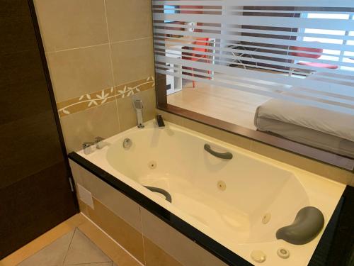 a bath tub in a bathroom with a window at HATAGO+ THE ALLEY in Taipei